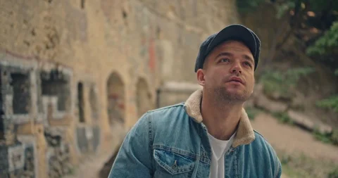 Handsome man in blue jeans jacket and white shirt, stylish hat looking around ri Stock Footage 117417546