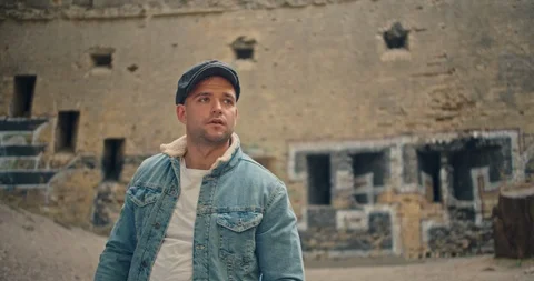 Handsome man in blue jeans jacket and white shirt, stylish hat looking around ri Stock Footage 117418049