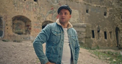 Handsome man in blue jeans jacket and white shirt, stylish hat looking around ri Stock Footage 117418481