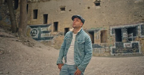 Handsome man in blue jeans jacket and white shirt, stylish hat looking around ri Stock Footage 117418702