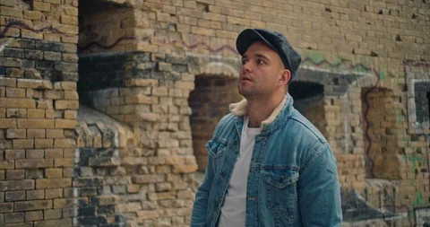 Handsome man in blue jeans jacket and white shirt, stylish hat looking around ri Stock Footage 117419200
