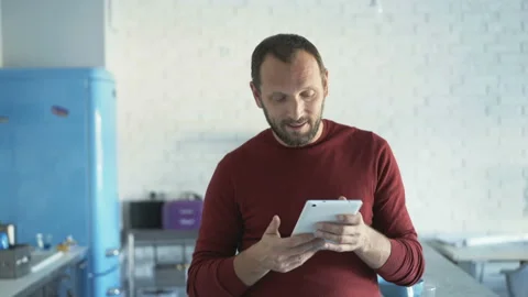 Handsome man browsing internet on tablet and smiling to the camera, steadycam sh Видео 93049854