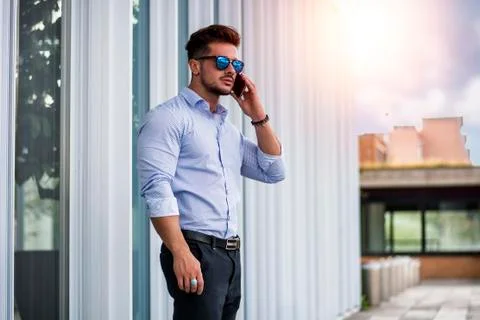 Handsome man calling on cellphone outside on urban background. Stock Photos