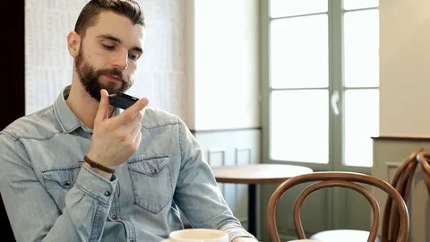 Handsome man chatting on loudspeaker in the cafe and looks satisfied, steadycam  Stock-Footage 73442189