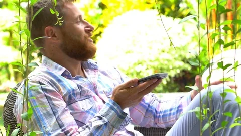 Handsome man chatting on loudspeaker while relaxing in the garden Stock-Footage 83241084