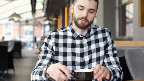 Handsome man in checked shirt drinking coffee and smiling to the camera, steady Video stock 73409013