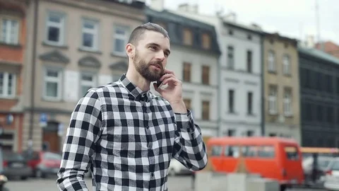 Handsome man in checked shirt standing in the old town and chatting on cellphone Video stock 73408732