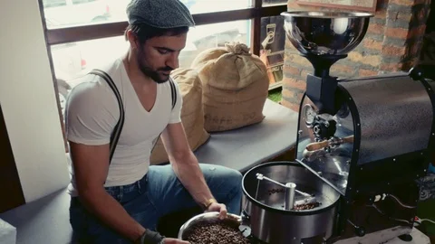 Handsome man checking roasted coffee beans from the roasting machine Stock Footage 95911877