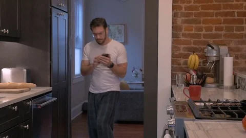 Handsome man dancing with his mobile smart phone exiting the kitchen Video stock 81844354