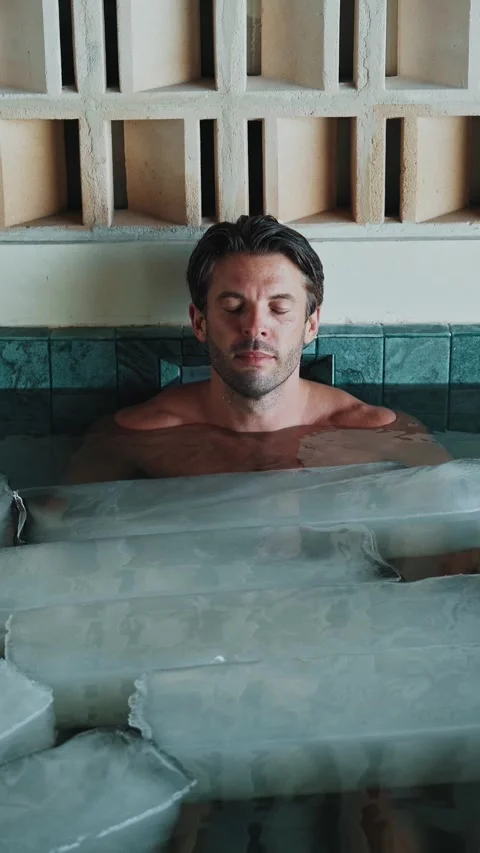 Handsome Man Diving into Cold Water of Swimming Pool with Ice Cubes for Body Stock Footage 318430367