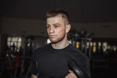 Handsome man doing biceps lifting with dumbbell on bench in a gym Stock Photos