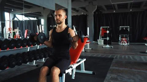 Handsome man doing exercise with one hand in fitness gym Stock Photos