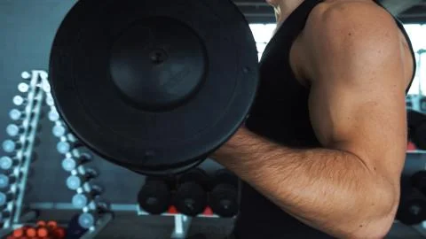 Handsome man doing exercise with one hand in fitness gym Stock Photos