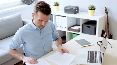 Handsome man doing paperwork at home office Video stock 65303073