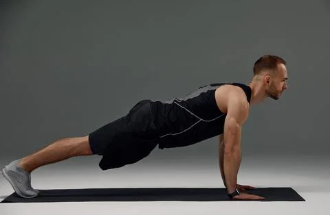 Handsome man doing plank exercise on floor indoors Stock Photos