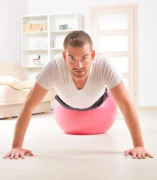 Handsome man doing push ups on the gym ball Stock Photos