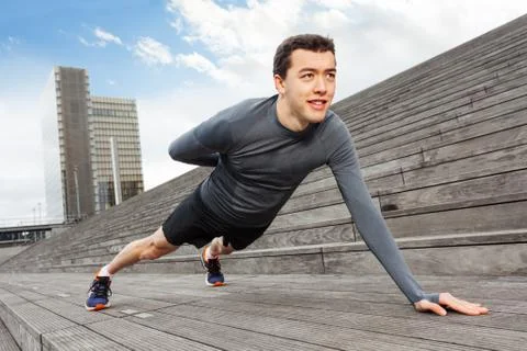 Handsome man doing push-ups on one hand outdoors Stock-Fotos