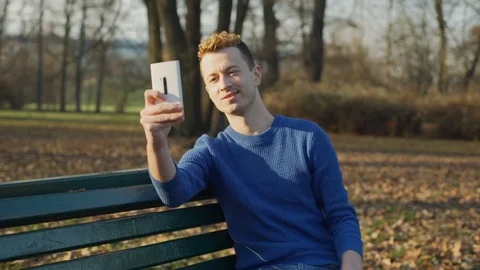 Handsome man doing selfies on smartphone in the park, steadycam shot Stock-Footage 70751414