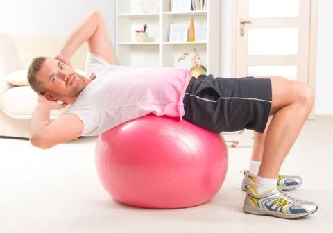Handsome man doing sit ups on the ball 스톡 사진