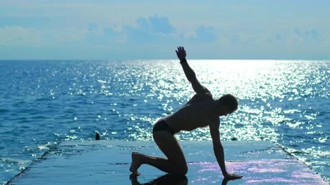 Handsome man doing stretching exercises on the background of the sea Stock Footage 142757964