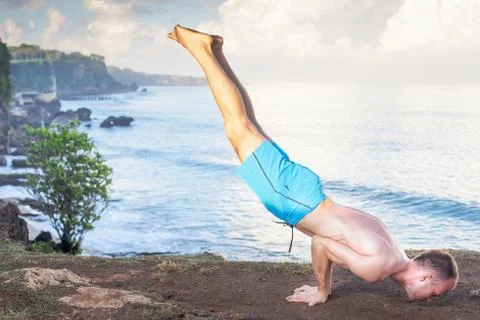 Handsome man doing yoga at cliff with blue sea background Stock Photos