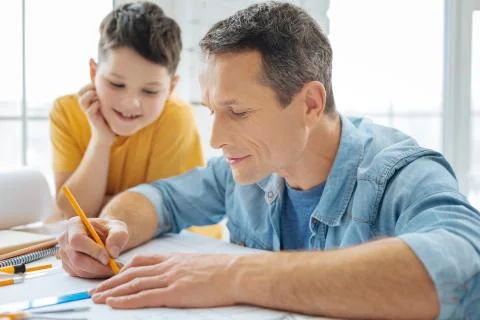 Handsome man drawing blueprint while his son watching Stock Photos