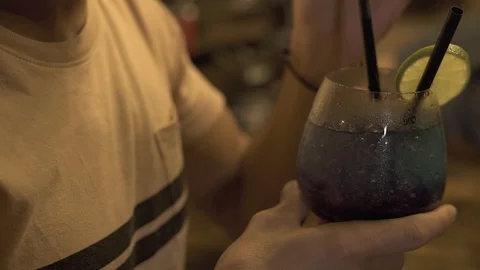 Handsome man drinking alcoholic cocktail from straw at bar counter in evening Stock Footage 101780827