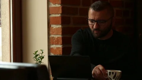 Handsome man drinking coffee in the cafe and smiling to the camera Video stock 80423675