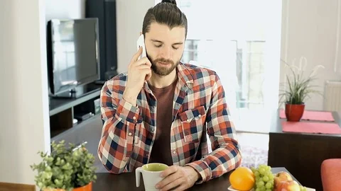Handsome man drinking coffee in the flat and chatting on cellphone, steadycam sh Vídeo Stock 75953002