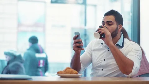 Handsome man drinking a cup of coffee, and smiling towards the phone screen Stock Footage 74000718