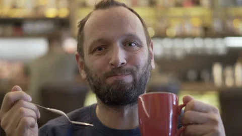 Handsome man drinking delicious cappuccino and smiling to the camera Stock Footage 88100925