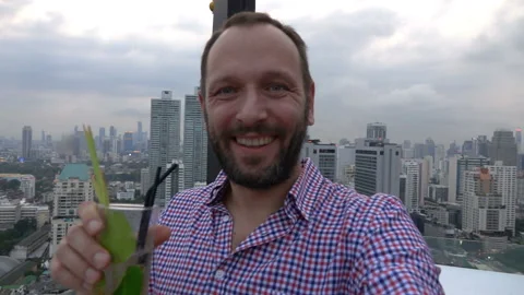 Handsome man drinking posh drink on the roof and doing selfie, slow motion shot  Stock Footage 87542787
