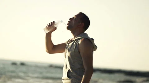 Handsome man drinking water on the beach, slow motion, shot at 240fps HD Stock Footage 56978954