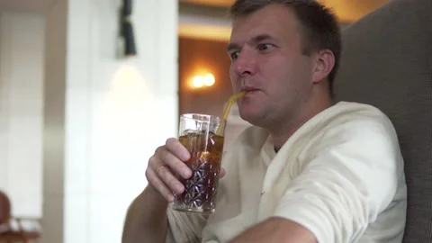 A handsome man drinks an alcoholic cocktail of whiskey with cola Stock Footage 232971538