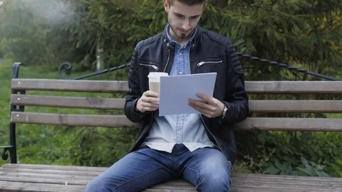 Handsome man drinks coffee and works with papers in park 4K Vídeo Stock 81972669