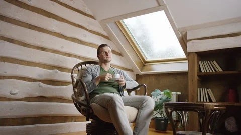 Handsome man drinks coffee on the attic Stock Footage 100346995