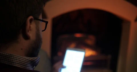 A handsome man drinks cognac and uses a tablet near the fireplace closeup Stock Footage 88058357