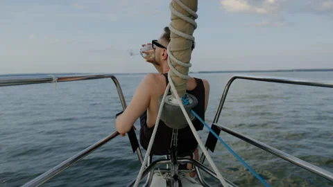 A handsome man drinks wine and rides a sailing yacht in the evening in summer Stock Footage 235995481