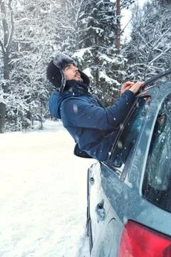 Handsome man driver looking out window of his car enjoying snowy day on count Stock Photos