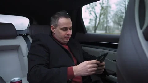 A handsome man in an elegant, expensive car, driving with his driver. A Stock-Footage 324963357