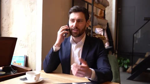 Handsome man in elegant style having talk on cellphone, sitting in cafe. Coffee Stock Footage 190461858