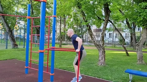 A handsome man is engaged on the uneven bars Stock Footage 197356775