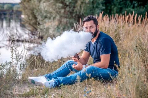 Handsome man enjoying an e-cigarette on the ground. Alternative to smoking. Foto stock