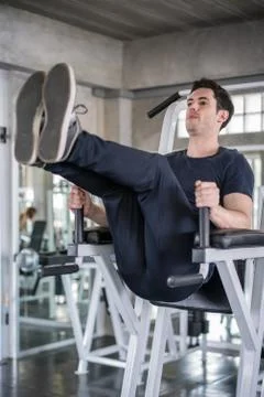 Handsome man exercising arm on machine builder muscles in fitness gym Stock Photos