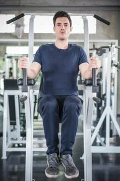 Handsome man exercising arm on machine builder muscles in fitness gym Stock Photos