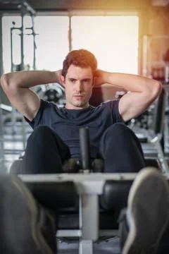 Handsome man exercising doing sit up abdominal exercise in gym Stock Photos