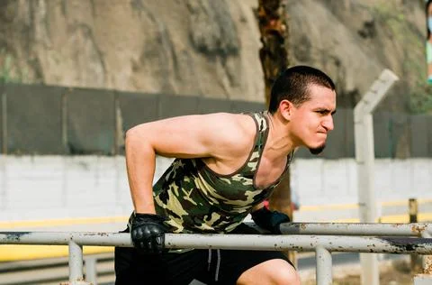 Handsome man exercising on parallel bars on the street outdoors. Stock Photos