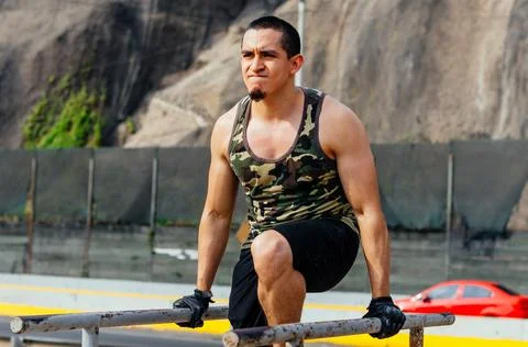 Handsome man exercising on parallel bars on the street outdoors. Stock-Fotos