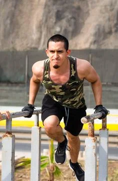 Handsome man exercising on parallel bars on the street outdoors. Stock Photos