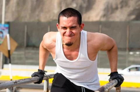 Handsome man exercising on parallel bars on the street outdoors. 写真素材